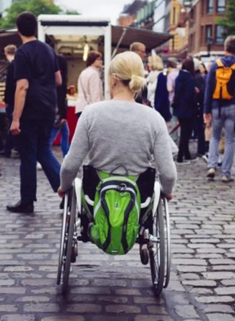 Eine Person mit Rollstuhl fährt über Kopfsteinpflaster