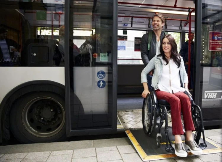 Eine Rollstuhlfahrerin rollt über die Rampe aus dem Bus heraus
